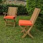 Coussins oranges présentés avec la chaise et le fauteuil de jardin Karimun